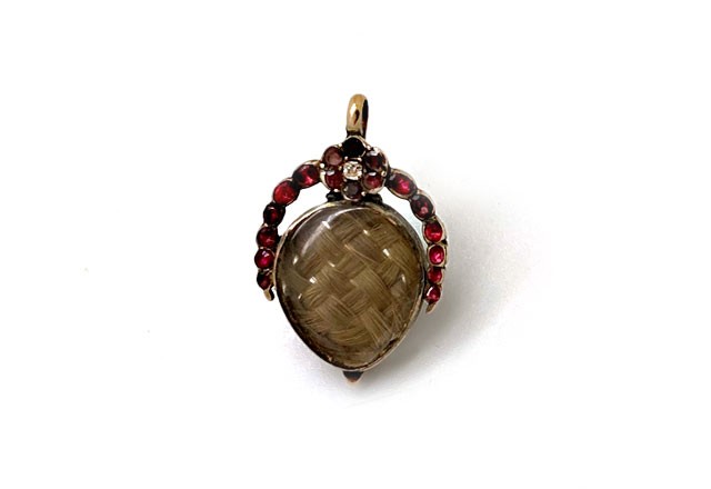 Antique Georgian mourning locket with hair weave inside. Surrounding garnets and a single diamond adorn the top. 14k Gold